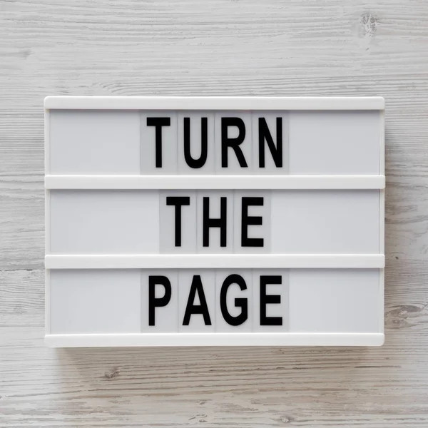 'Turn the page' words on a modern board on a white wooden surfac