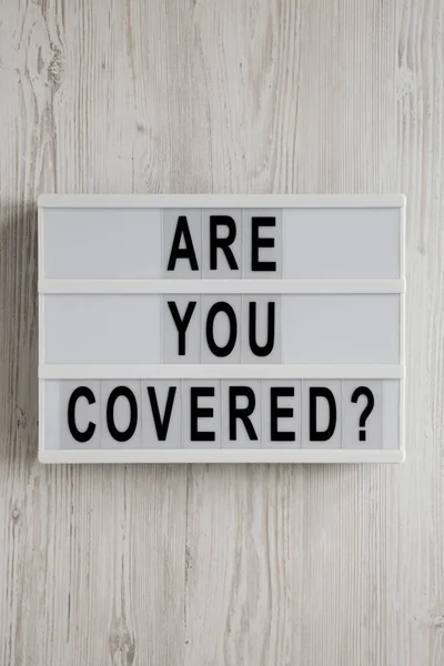 \'Are you covered?\' words on a modern board on a white wooden sur