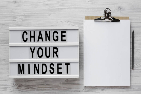 'Change your mindset' words on a lightbox, clipboard with blank 