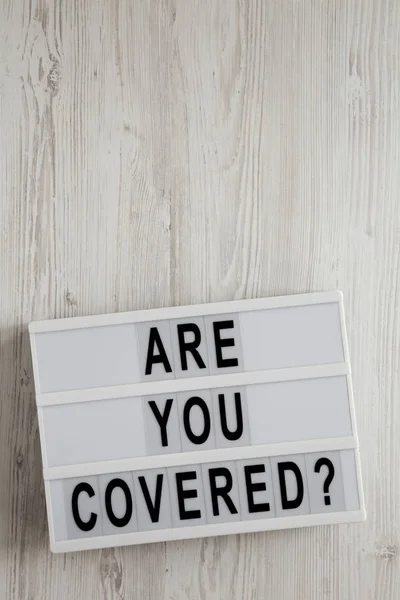 \'Are you covered?\' words on a modern board on a white wooden bac