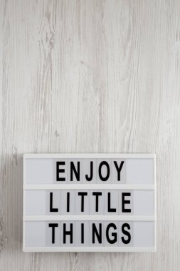 Beyaz bir sörf tahtasında ışık kutusunda küçük şeylerin tadını çıkar.