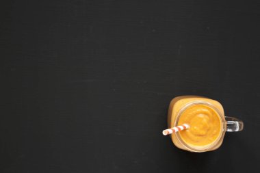 Siyah arka planda cam bir kavanozda ev yapımı balkabağı püresi., 