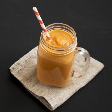 Siyah yüzey üzerinde cam kavanozda ev yapımı balkabağı püresi.,