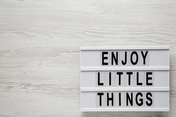 "Απολαύστε μικρά πράγματα" λέξεις σε ένα σύγχρονο πίνακα σε ένα λευκό ξύλινο — Φωτογραφία Αρχείου