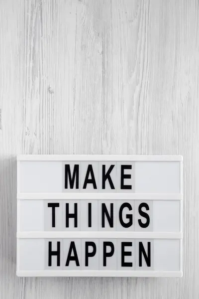 \'Make things happen\' words on a modern board on a white wooden b