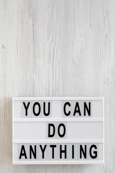 \'You can do anything\' words on a lightbox on a white wooden back
