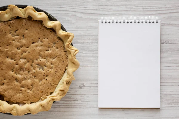 Vue du dessus, Tarte Derby aux noix au chocolat maison, bloc-notes vierge sur — Photo