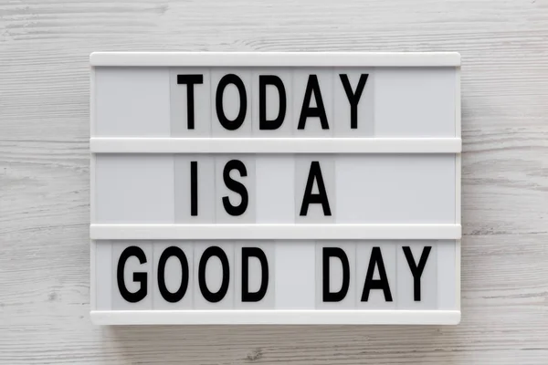 "Σήμερα είναι μια καλή μέρα" λέξεις σε ένα lightbox σε ένα λευκό ξύλινο πίσω μέρος — Φωτογραφία Αρχείου