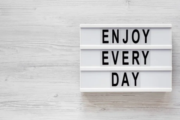 'Enjoy every day' words on a modern board on a white wooden surf — Stock Photo, Image