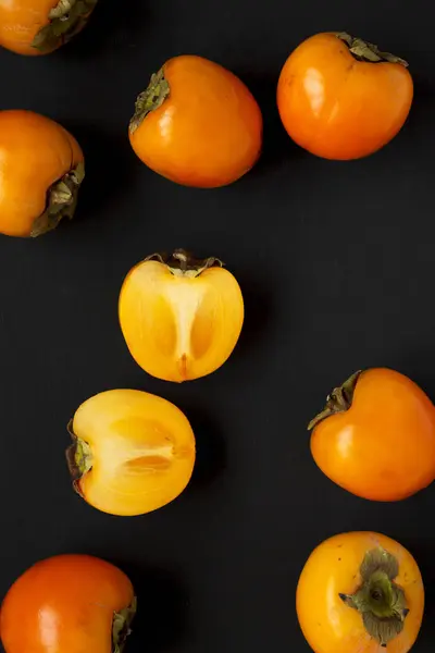 Raw maduro laranja caqui na superfície preta, vista superior. Depósito plano , — Fotografia de Stock