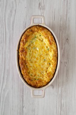 Beyaz ahşap bir sırtta ev yapımı Çedar Mısırlı Puding Güveci.