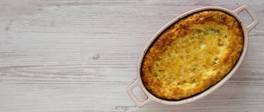 Beyaz ahşap bir surfac üzerinde ev yapımı çedar mısır pudingi güveci.