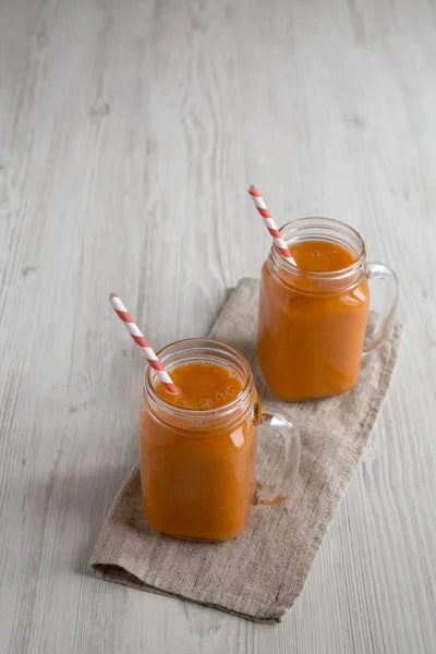 Domácí mango mrkev Smoothie ve skleněných sklenicích přes bílou dřevěnou b — Stock fotografie