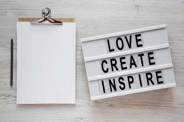 'Love create inspire' words on a lightbox, clipboard with blank — 스톡 사진