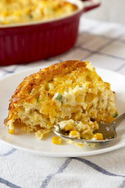 Homemade Cheddar Corn Pudding Casserole on a white plate, side v