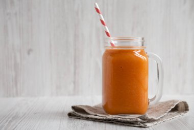 Ev yapımı Mango Havuç Smoothie, cam bir kavanozda beyaz kupa üzerinde.
