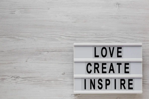 'Love create inspire' words on a lightbox on a white wooden back — 스톡 사진