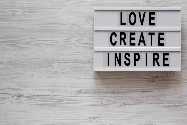 'L'amore crea ispirare 'parole su una tavola moderna su un legno bianco — Foto Stock