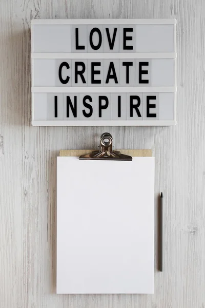 'Love create inspire' words on a lightbox, clipboard with blank — 스톡 사진