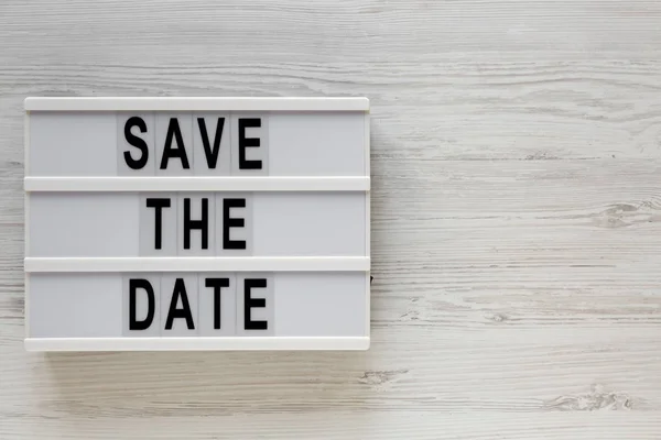 Mots "Save the date" sur une planche moderne sur une surfac en bois blanc — Photo