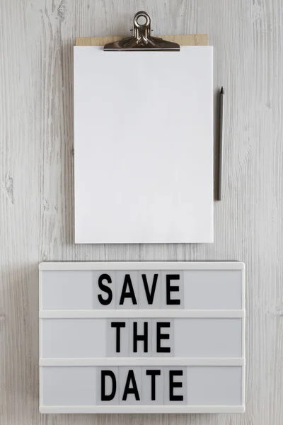 'Save the date' woorden op een lichtbak, klembord met blanco vel — Stockfoto