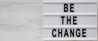 Beyaz ahşap bir surfac üzerinde modern bir tahtada 'Değişim ol' kelimeleri