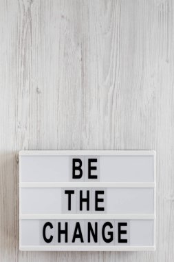 Beyaz ahşap bir surfac üzerinde modern bir tahtada 'Değişim ol' kelimeleri