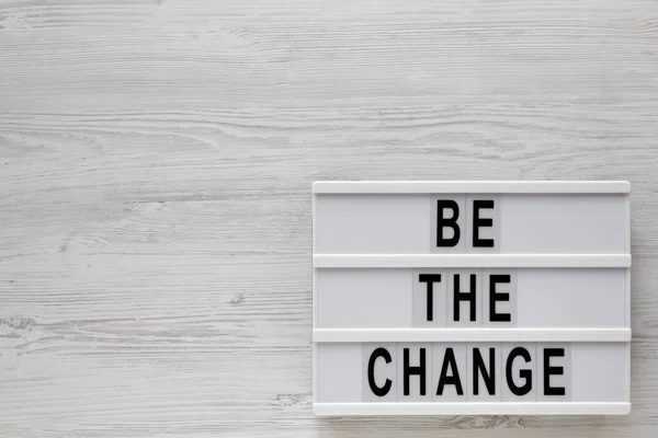 "Γίνε η αλλαγή" λέξεις σε ένα lightbox σε ένα λευκό ξύλινο φόντο — Φωτογραφία Αρχείου