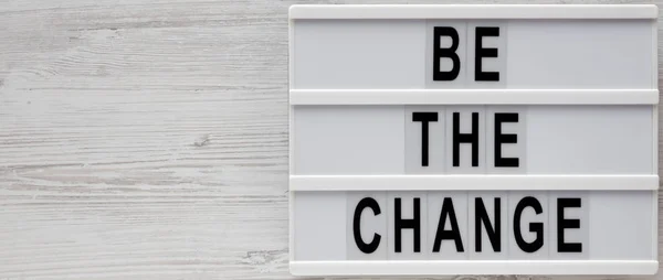 \'Be the change\' words on a modern board on a white wooden surfac