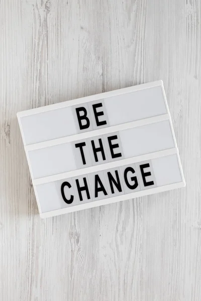 \'Be the change\' words on a lightbox on a white wooden background