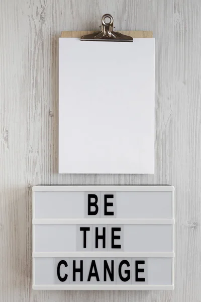 stock image 'Be the change' words on a lightbox, clipboard with blank sheet 