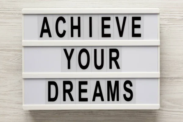 "Réalisez vos rêves" mots sur une lightbox sur un dos en bois blanc — Photo