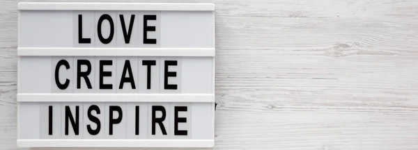 'Love create inspire' words on a lightbox on a white wooden back — 스톡 사진