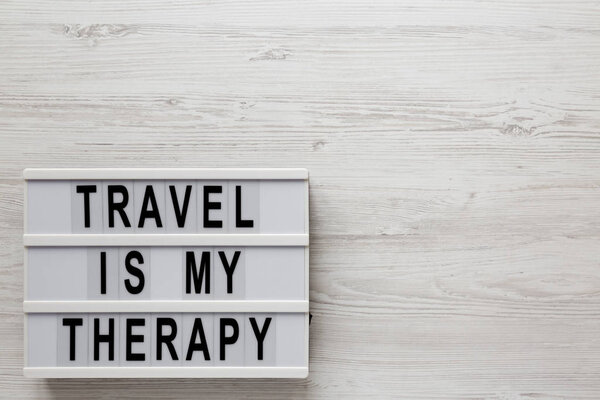 "Путешествие это моя терапия" слова на светильнике на белом деревянном балконе
