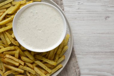 Beyaz ahşap bir tabakta ev yapımı çıtır patates kızartması.