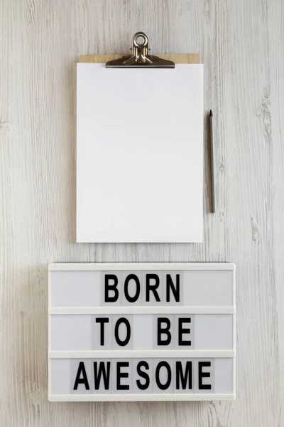 "Born to be awesome" words on a lightbox, clipboard with blank s — стоковое фото