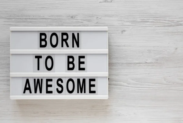 'Born to be awesome' words on a lightbox on a white wooden backg — Stock Photo, Image