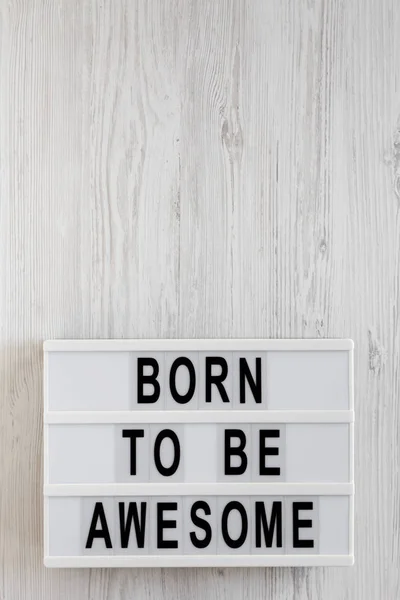 Palabras 'Nacido para ser impresionante' en una caja de luz en un respaldo de madera blanca — Foto de Stock