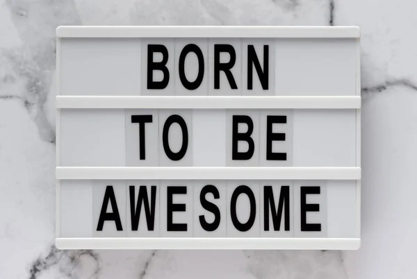 Palabras 'Nacido para ser impresionante' en una caja de luz sobre un fondo de mármol , — Foto de Stock