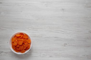 Beyaz ahşap kapta taze çiğ organik havuç cipsi.