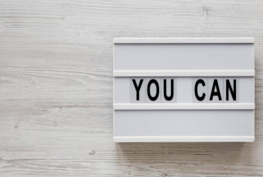 Beyaz ahşap arka planda modern bir tahtada 'Yapabilirsin' kelimeleri, 