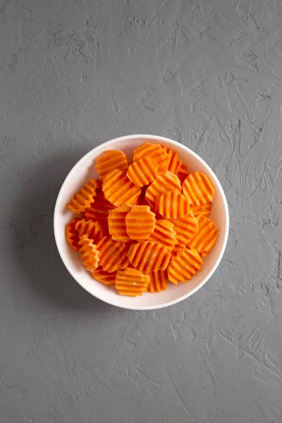 Fresh Raw Organic Carrot Chips in a bowl over gray surface, top — Stock Photo, Image