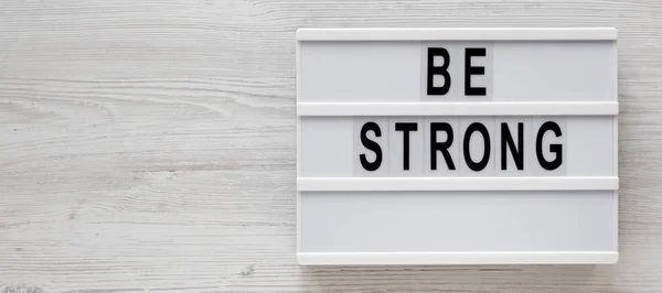"Soyez forts" mots sur une lightbox sur un fond en bois blanc, à — Photo
