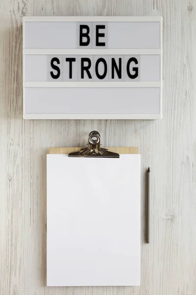 'Be strong' words on a lightbox, noticepad with blank sheet of p — Stock Photo, Image