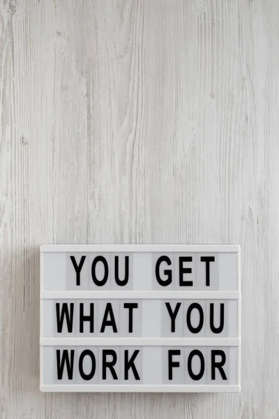 \'You get what you work for\' words on a modern board on a white w