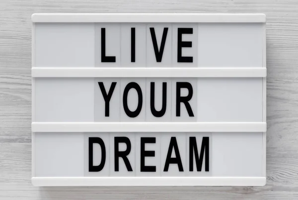 在白色木制背木板上的现代板上写着"实现你的梦想" — 图库照片