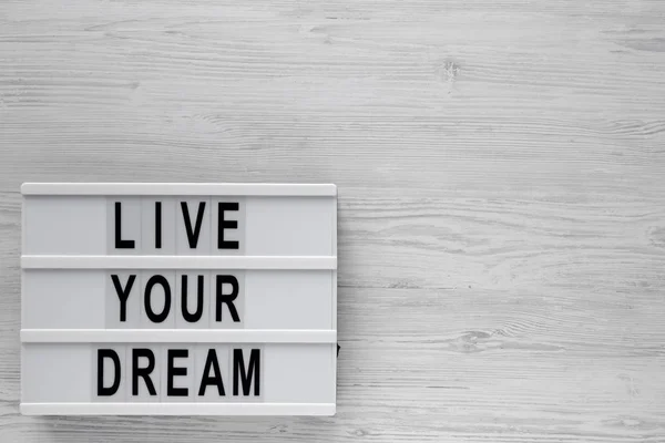 \'Live your dream\' words on a lightbox on a white wooden backgrou