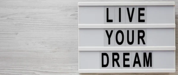 \'Live your dream\' words on a modern board on a white wooden back