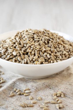 Çiğ Ayçiçeği Çekirdekleri beyaz bir kasede beyaz ahşap bir sur üzerinde