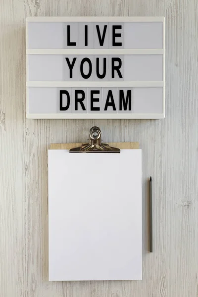 \'Live your dream\' words on a lightbox, clipboard with blank shee